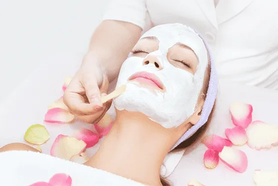 Facial treatment with a cream mask, surrounded by rose petals